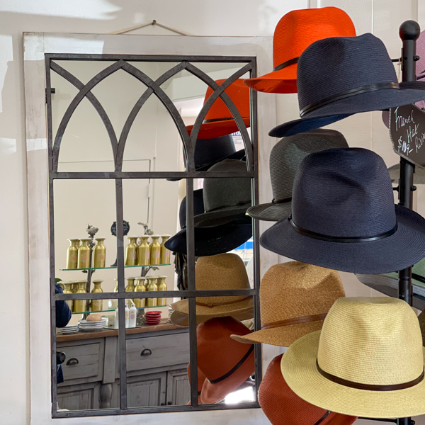 colorful straw hats hanging from a coat rack